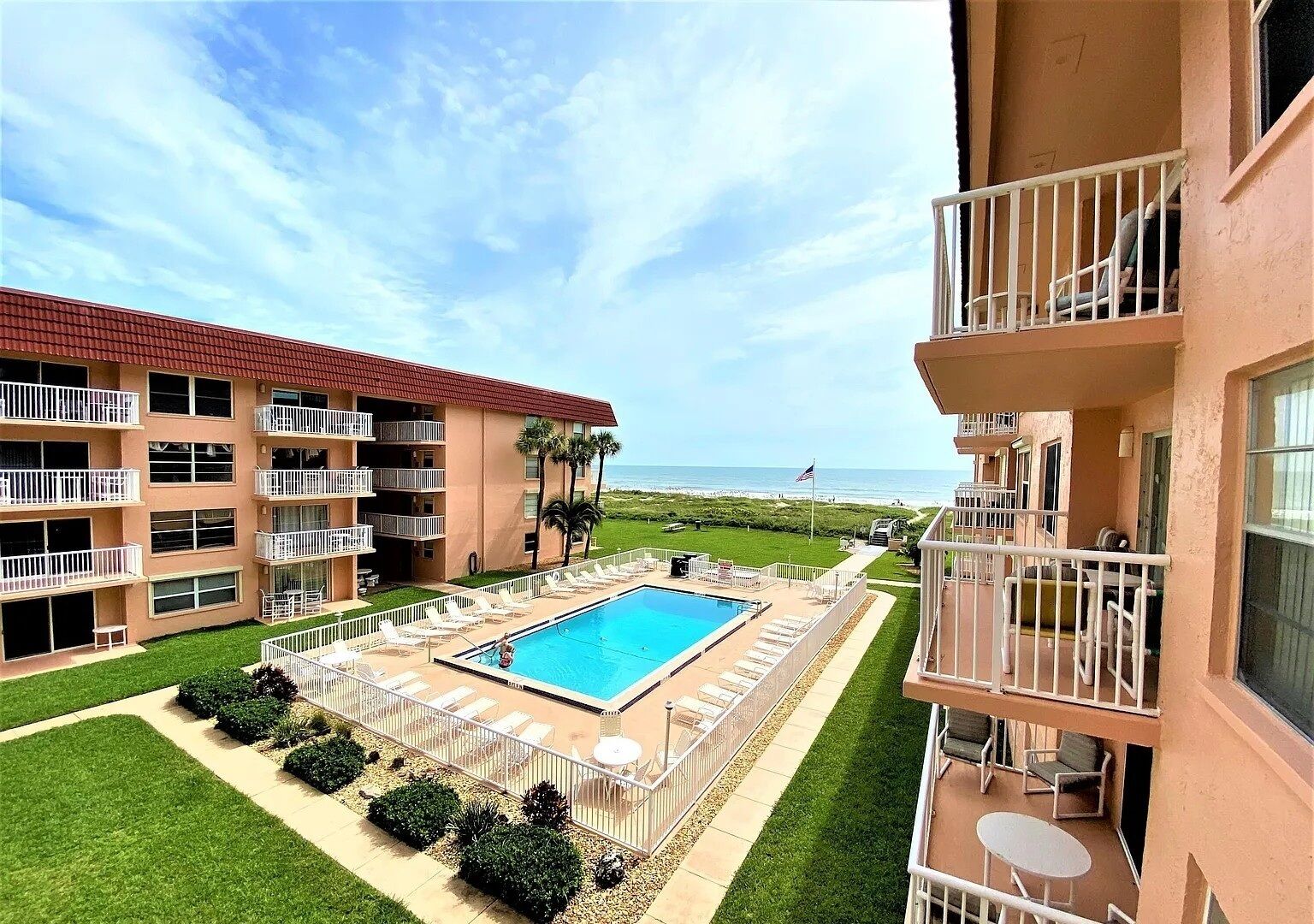 A hotel with a swimming pool, multiple balconies, and a view of the beach.