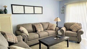 A living room with a sofa set, a coffee table, and a lamp. - Direct Oceanfront 3-bedroom Condo in Cocoa Beach (Cocoa Beach)