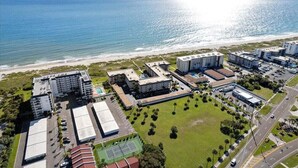 An aerial view of a coastal hotel complex with multiple buildings, a beach, and a clear view of the ocean. - Direct Oceanfront 3-bedroom Condo in Cocoa Beach (Cocoa Beach)