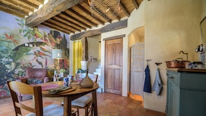 A rustic dining area with wooden furniture, a mural of birds, and a tiled floor. - Duplex studio "La Volière" 10 minutes from Lectoure, Fleurance and Condom (Terraube)