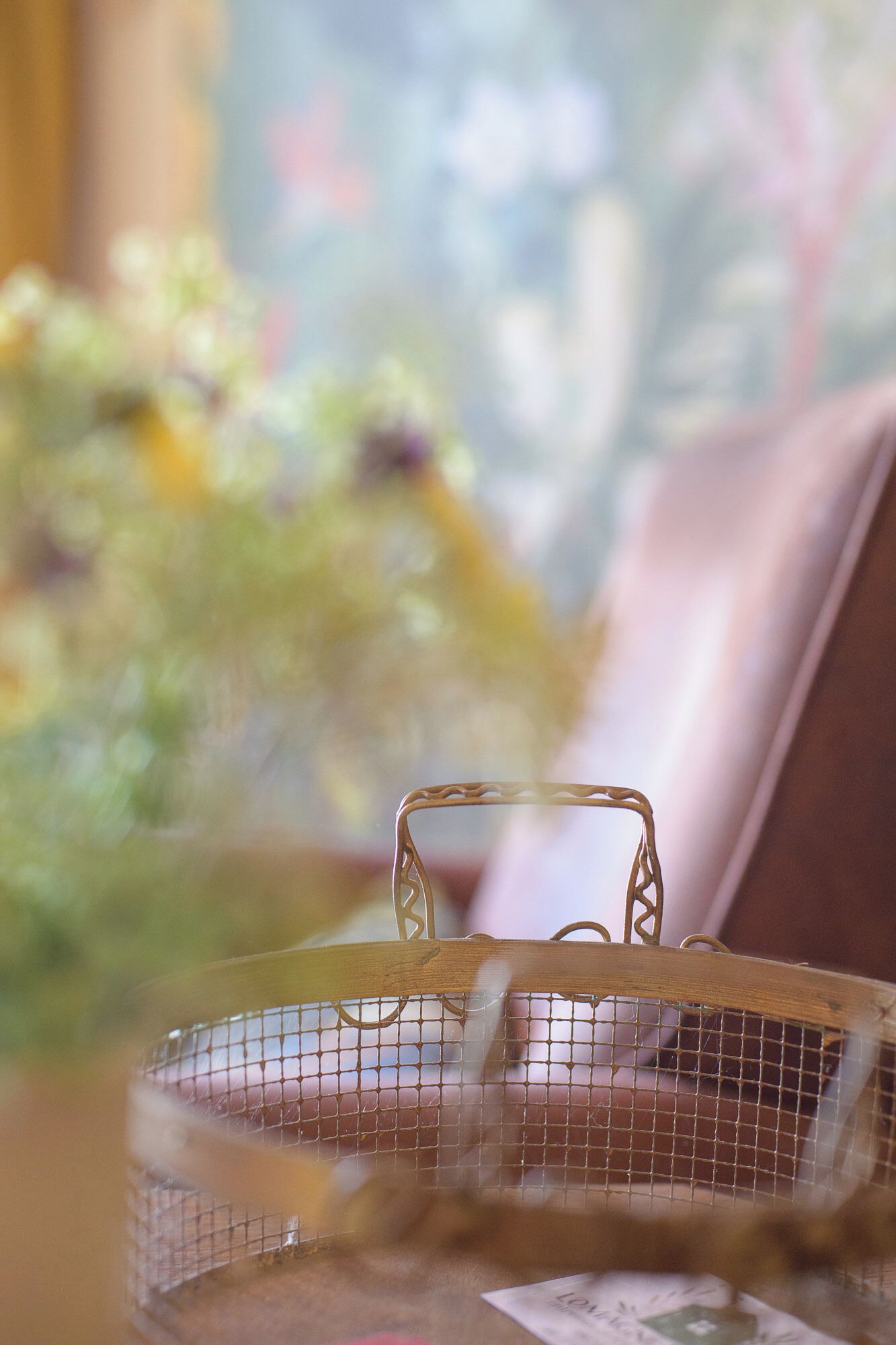 A birdcage with a wire mesh and a wooden frame, placed on a surface with a blurred background.