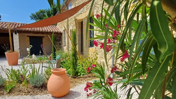 A courtyard with a stone building, a large terracotta pot, and various plants and flowers. - Duplex studio "La Volière" 10 minutes from Lectoure, Fleurance and Condom (Terraube)
