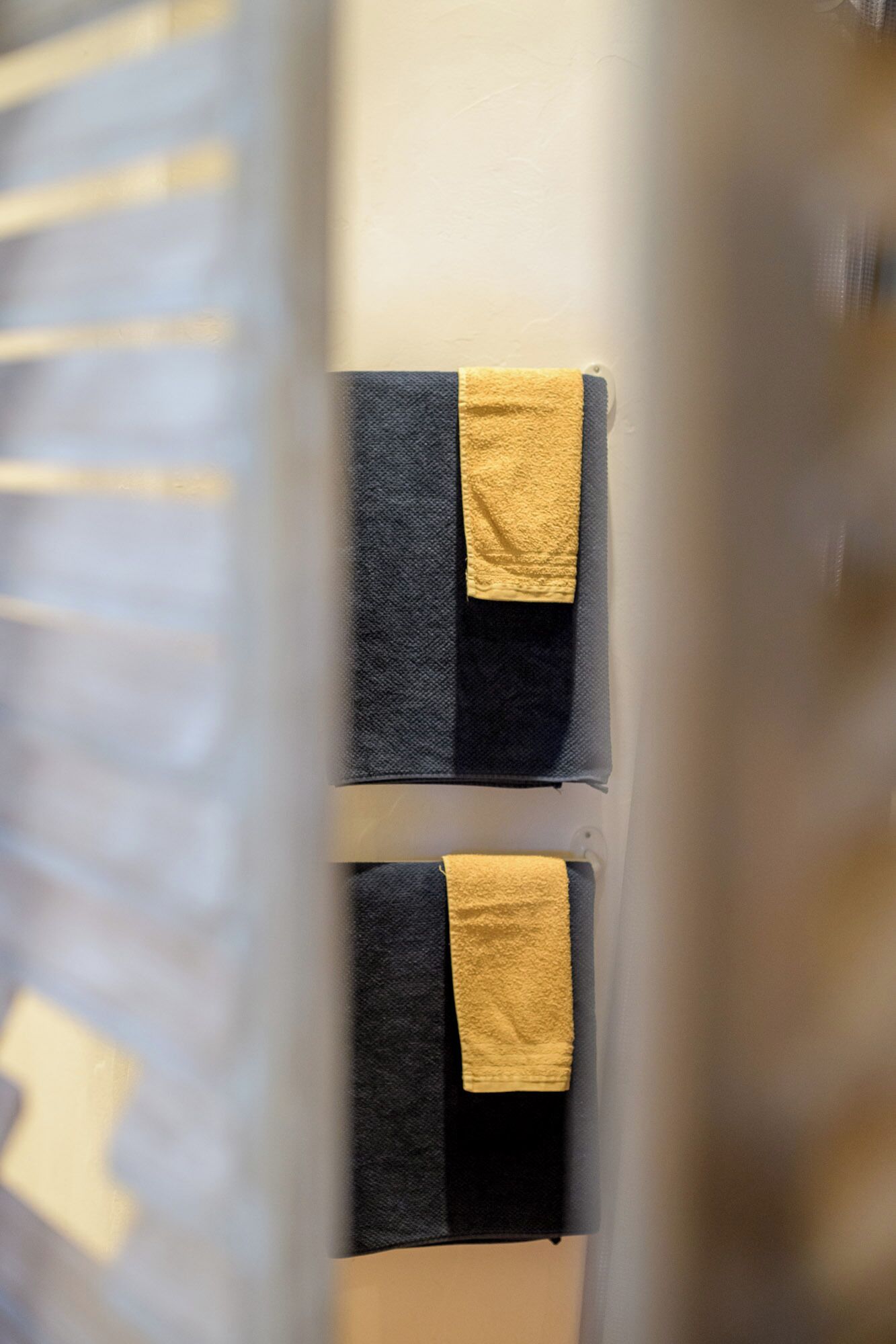 A bathroom with two towels hanging on a rack, one black and one yellow.