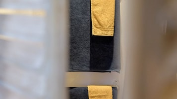 A bathroom with two towels hanging on a rack, one black and one yellow.