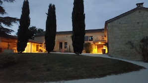A stone building with a courtyard, tall cypress trees, and a warm-lit entrance. - Duplex studio "La Volière" 10 minutes from Lectoure, Fleurance and Condom (Terraube)