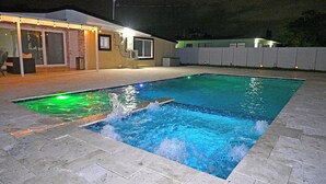 En swimmingpool med et klart vandfald og en flisbelagt terrasse.