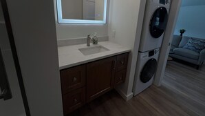 A modern bathroom with a large mirror, a sink, and a washing machine.