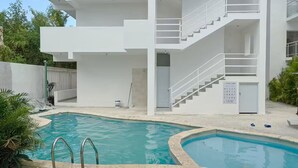 Un immeuble moderne à plusieurs étages, avec une piscine en premier plan.