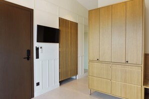 Un couloir avec une armoire en bois, une porte blanche et un téléviseur fixé au mur.