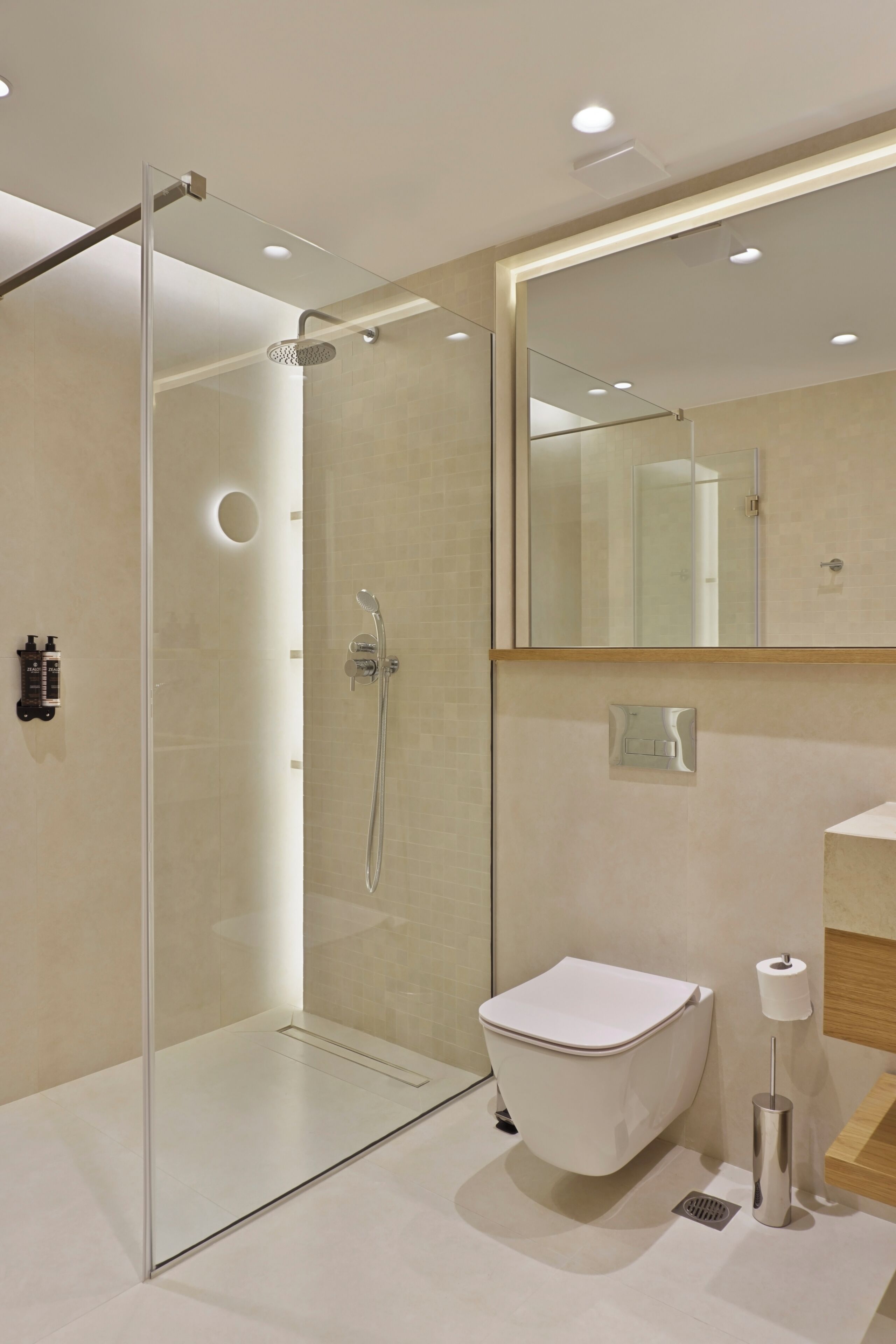 A modern bathroom with a glass shower enclosure, a white toilet, and a mirror above the sink.