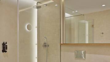 Un baño moderno con cabina de ducha de vidrio, un inodoro blanco y un espejo sobre el lavabo.