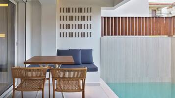 A modern interior with a wooden ceiling, a glass door, a sofa with blue cushions, a wooden table, and two wicker chairs.