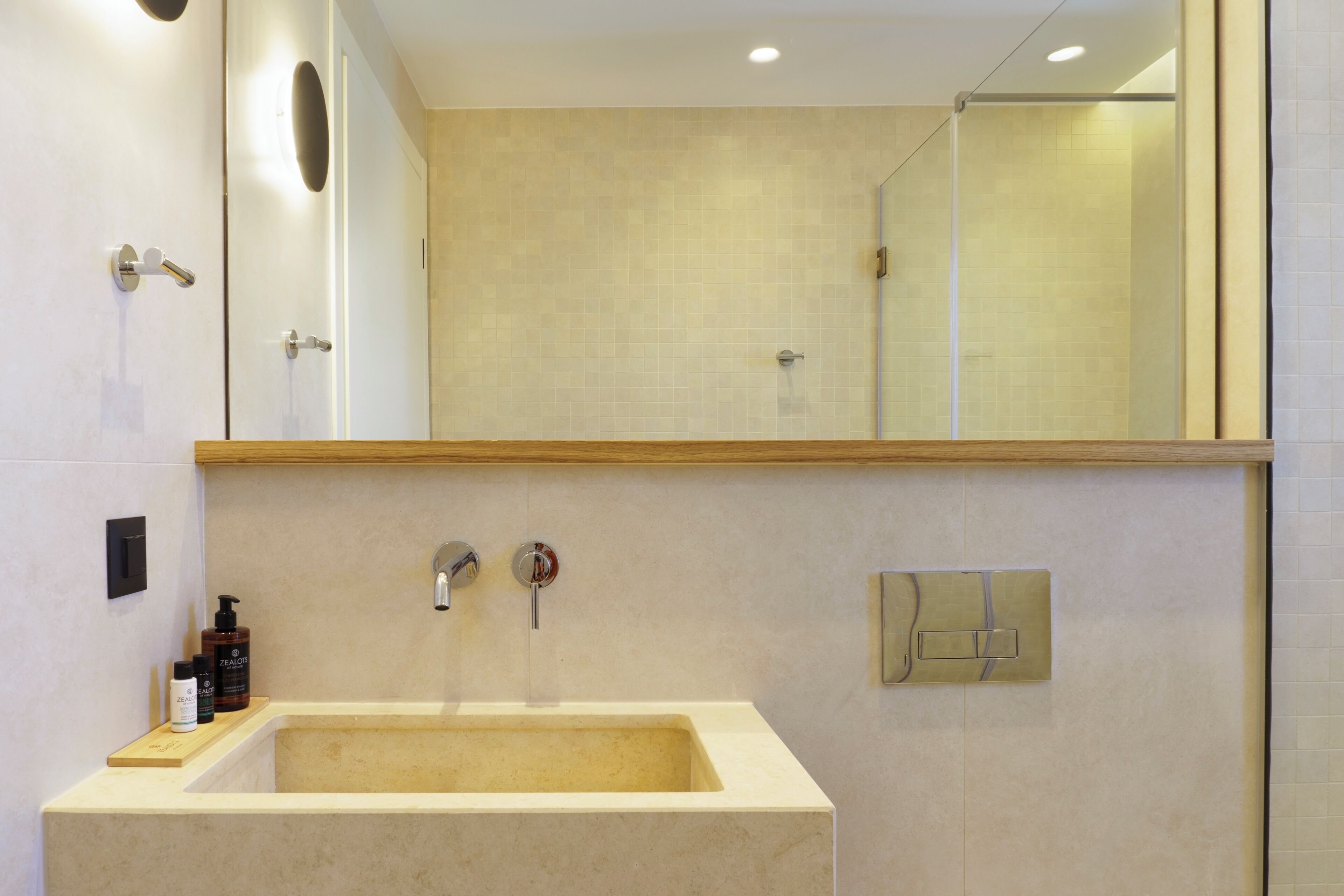 A modern bathroom with a large sink, a mirror, and a shower area.