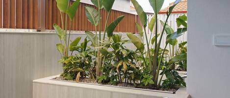 A swimming pool with a metal ladder, surrounded by plants and a wooden ceiling.