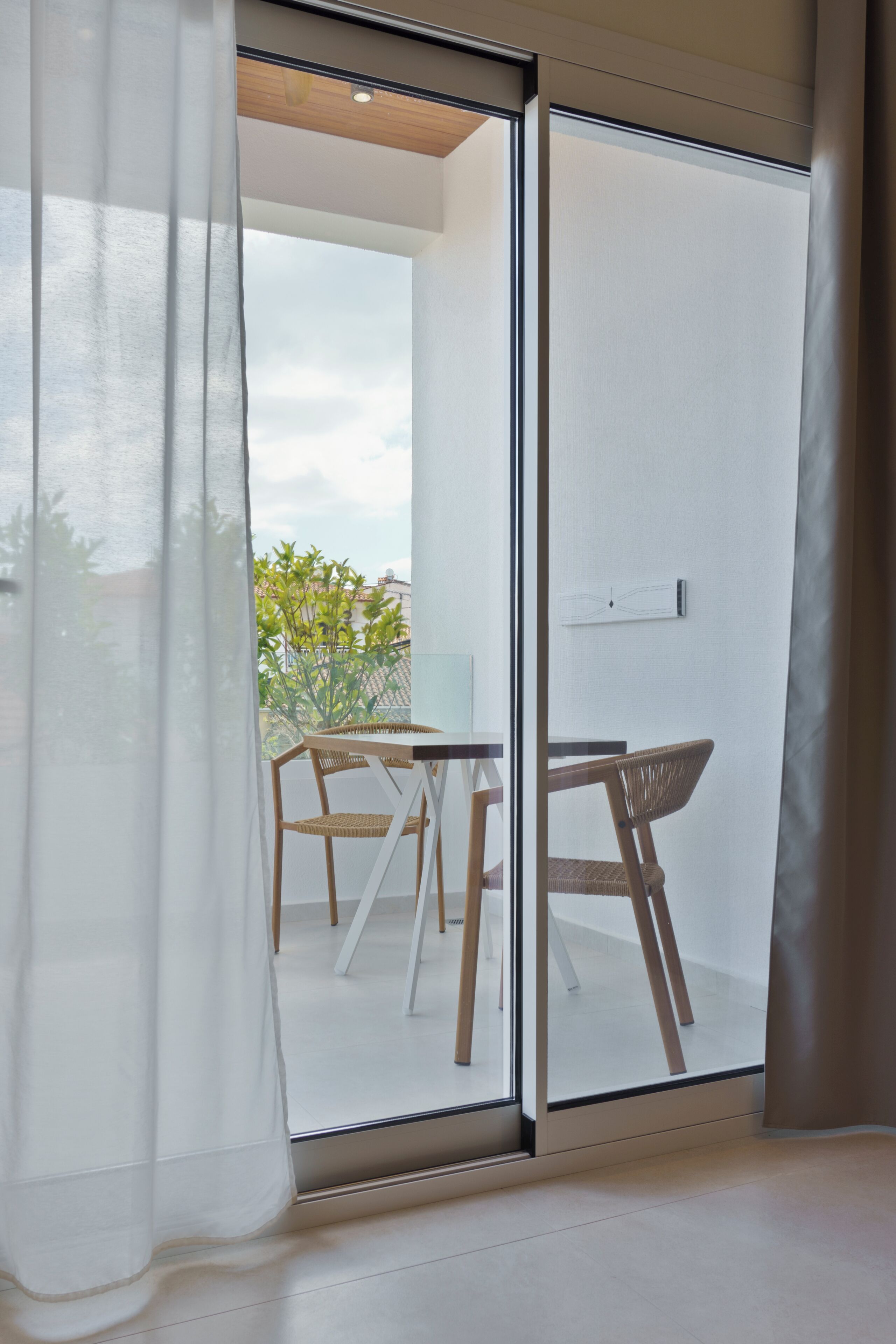 A modern room with a sliding glass door leading to an outdoor area with a table and chairs.