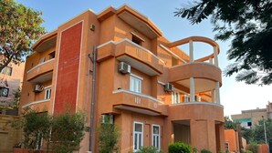 Un immeuble résidentiel à plusieurs étages, doté de balcons, de climatiseurs et d’une cour dallée.