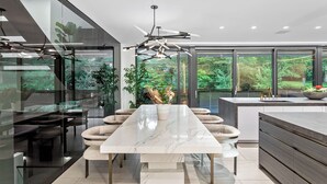 A modern kitchen with a marble countertop, a central island, and a dining area with a glass partition.
