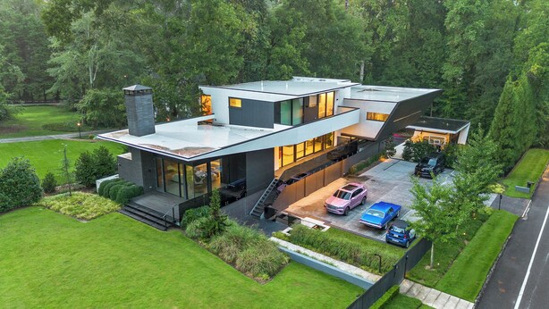 A modern two-story house with a flat roof, large windows, and a covered driveway.