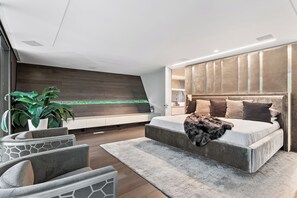 A modern bedroom with a large bed, a seating area with a sofa and chairs, a potted plant, and a wooden wall. - Contemporary Modern estate in delightful Atlanta with an infinity swimming pool (Atlanta)