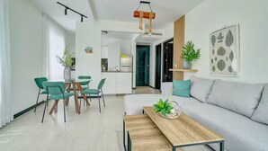 Ein modernes Wohnzimmer mit einer Couch, einem Holztisch und einem Essbereich mit grünen Stühlen.