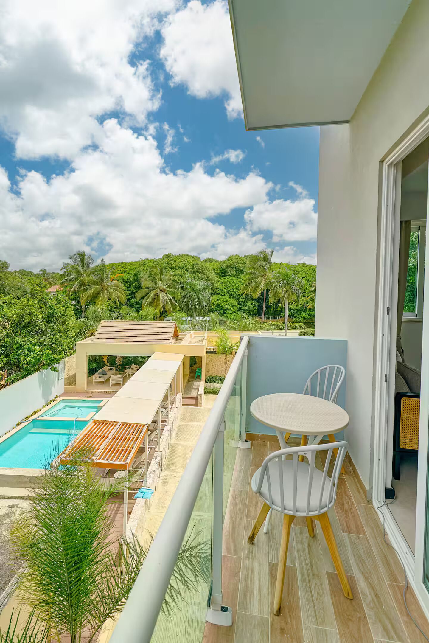 Un balcon avec une piscine, des chaises et une vue sur un paysage luxuriant.