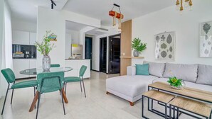 Ein modernes Wohnzimmer mit Sofa, Couchtisch und Essbereich mit Stühlen und Tisch.