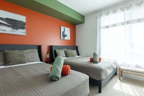 A hotel room with two beds, a green accent wall, and a large window with sheer curtains. - Charming, Peaceful Apartment Retreat in Griffith (Glendale)
