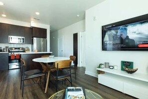 A modern kitchen with dark cabinets, stainless steel appliances, and a dining area with a round table and chairs.