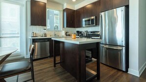 Una cocina moderna con armarios de madera oscura, electrodomésticos de acero inoxidable y una isla central.
