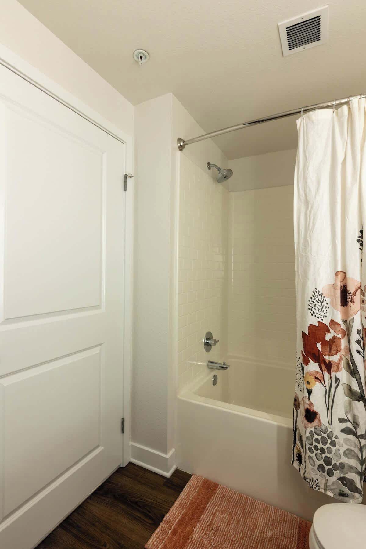 A bathroom with a shower, toilet, and a door.