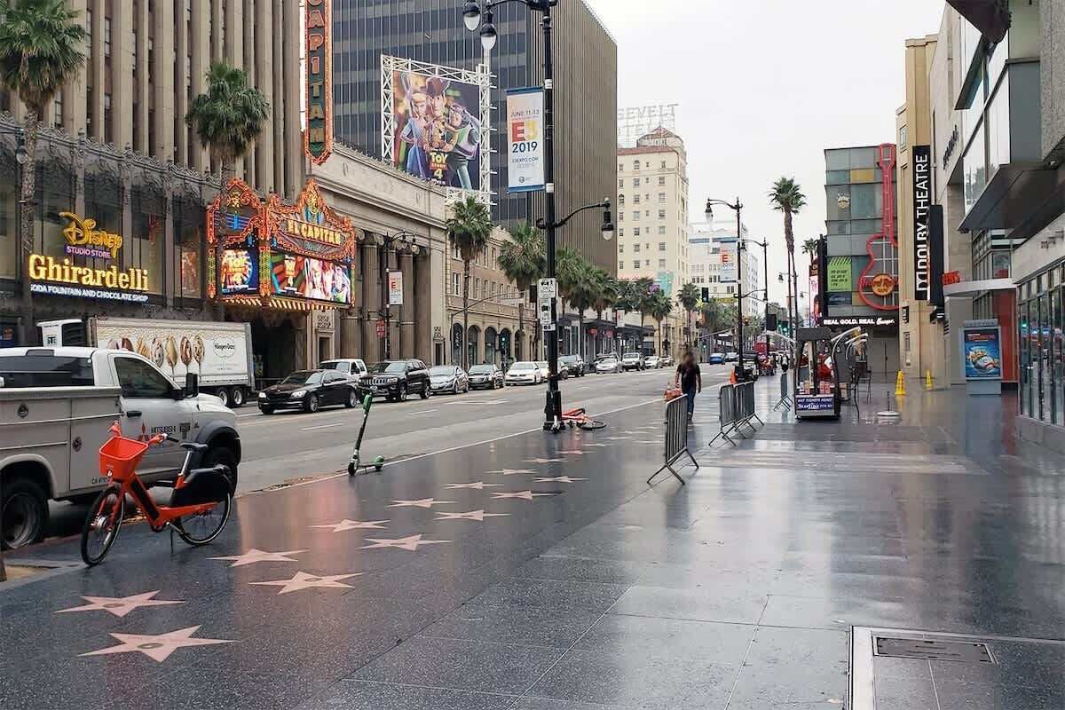 A street with a sidewalk, palm trees, and a building with a sign for the Ghirardelli Chocolate Shop.