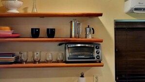 A kitchen with wooden shelves holding dishes, glasses, and a coffee pot. A toaster oven is on the lower shelf. - The Gold heart of Grass Valley (Grass Valley)
