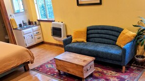 A cozy room with a blue sofa, a wooden chest, and a colorful rug. - The Gold heart of Grass Valley (Grass Valley)