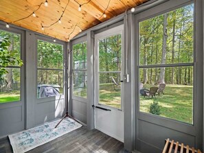 Una habitación con ventanas amplias, techo de madera y vista a un espacio exterior con césped.