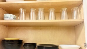A kitchen shelf with clear glass jars, black and white bowls, and a white sink. - Terrific 2-bedroom house with AC in Dallas (Dallas)