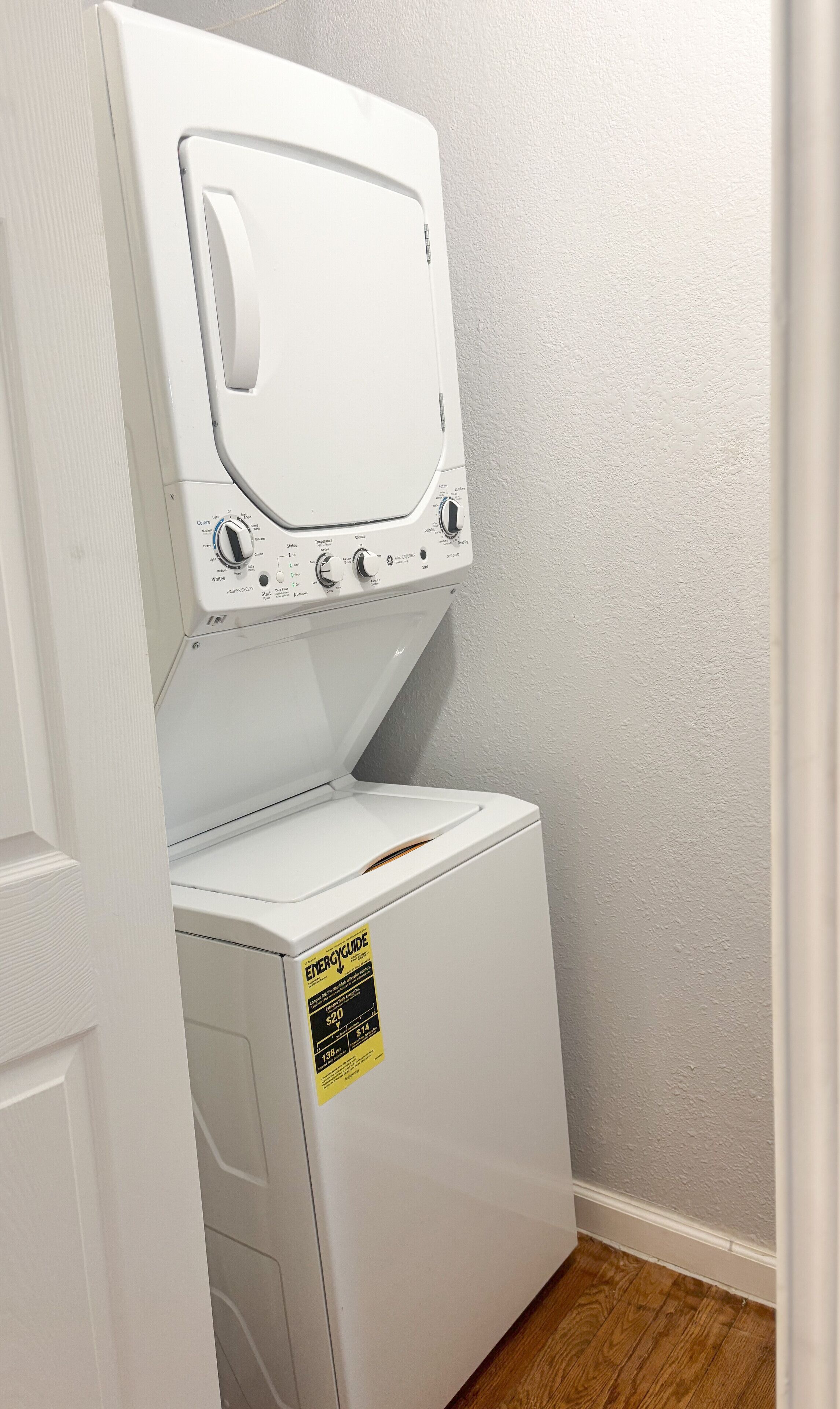 Un appareil combiné lave-linge et sèche-linge, de type « superposé », muni d’une étiquette indiquant sa consommation énergétique.