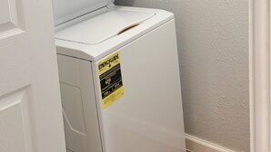A front-loading washer and dryer unit with an ENERGY GUIDE sticker, located in a room with wooden flooring and a textured wall. - Terrific 2-bedroom house with AC in Dallas (Dallas)