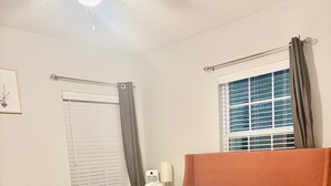 A bedroom with a bed, a nightstand, a window with curtains, and a ceiling fan. - Terrific 2-bedroom house with AC in Dallas (Dallas)