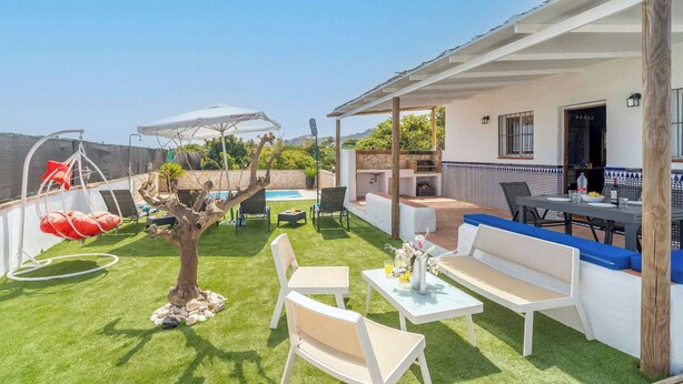 A patio with a pool, outdoor seating, and a covered area with a table and chairs.