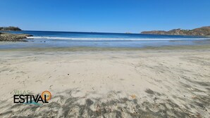 A beach with clear skies, calm waters, and rocky outcrops. - Villas Estival Playa Prieta (Tempate)