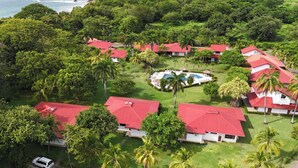 A resort with multiple buildings, a swimming pool, and lush greenery. - Villas Estival Playa Prieta (Tempate)