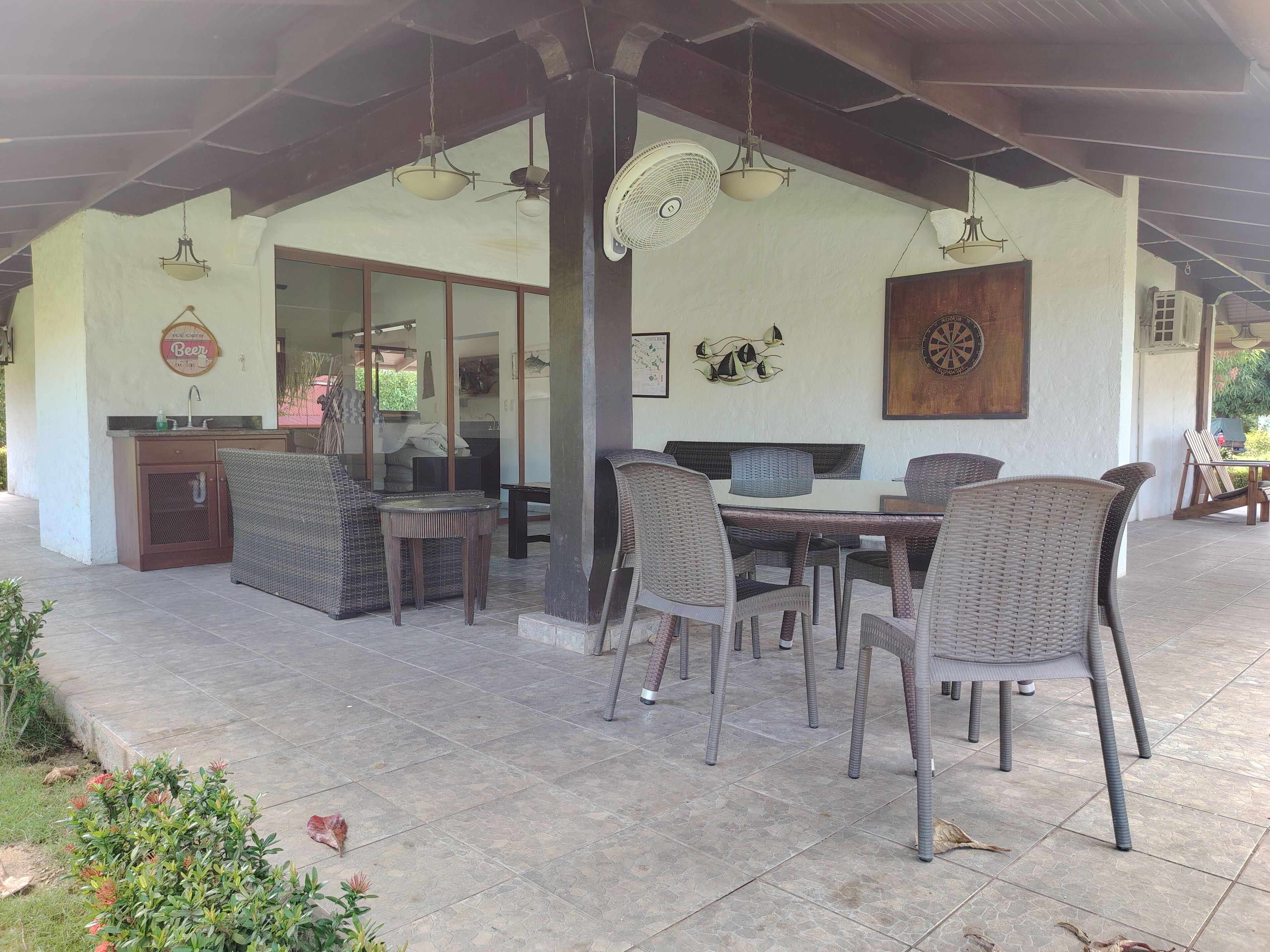 An outdoor patio with wicker furniture, a dining table, and a kitchen area with a sink and cabinets.