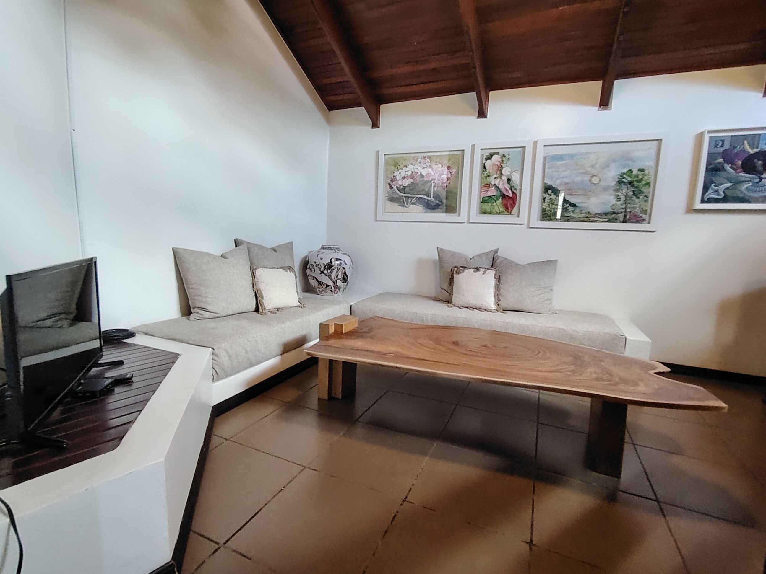 A living room with a sofa, a coffee table, a TV, and artwork on the wall.