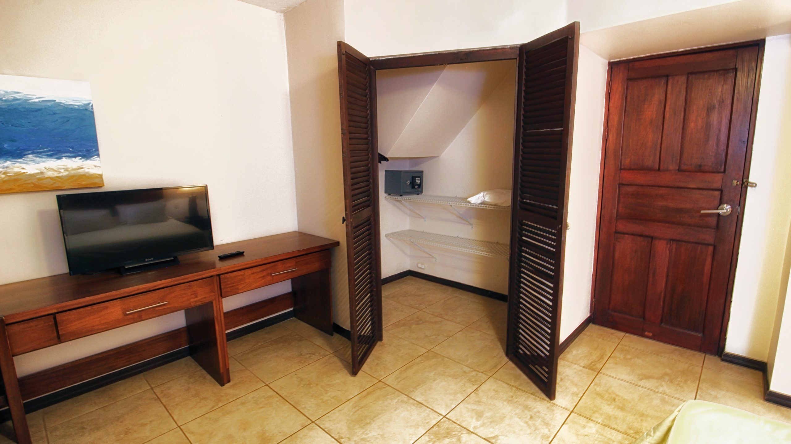Una habitación compacta con un escritorio de madera, un televisor y un armario.