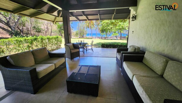 A covered outdoor seating area with wicker furniture and a view of the sea. - Villas Estival Playa Prieta (Tempate)
