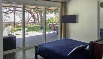 Un dormitorio con cama, televisor y vista a un patio exterior con sillas y una mesa.