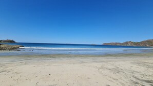 A beach with clear skies, calm waters, and rocky outcrops. - Villas Estival Playa Prieta (Tempate)