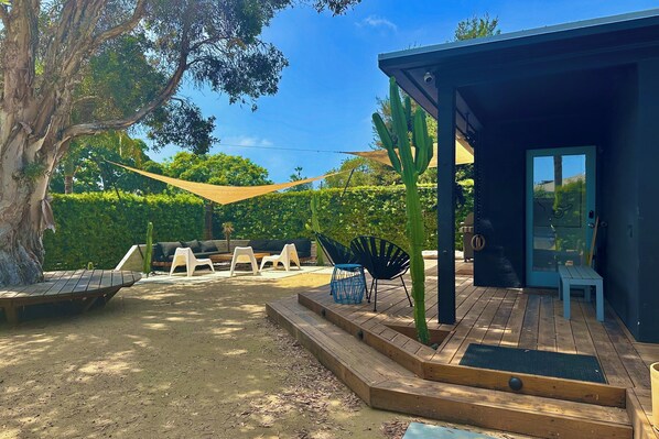 A wooden deck with a bench, a table, and a chair.