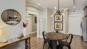 A modern kitchen with stainless steel appliances, a round dining table with chairs, and a chandelier.