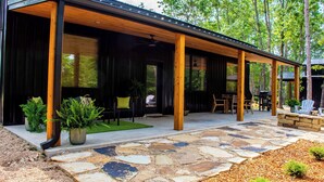 Un patio couvert doté d’un sol en pierre, de poutres en bois et de mobilier d’extérieur.